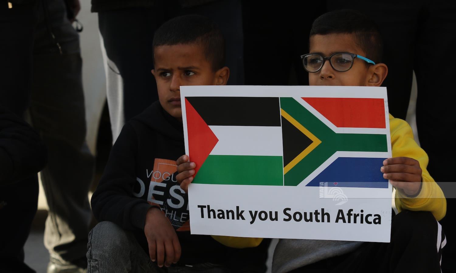 طفل يرفع لافتة تحمل العلمين الفلسطيني والجنوب إفريقي وعبارة "شكرًا جنوب إفريقيا" (تصوير: مشهور وحواح/وفا)